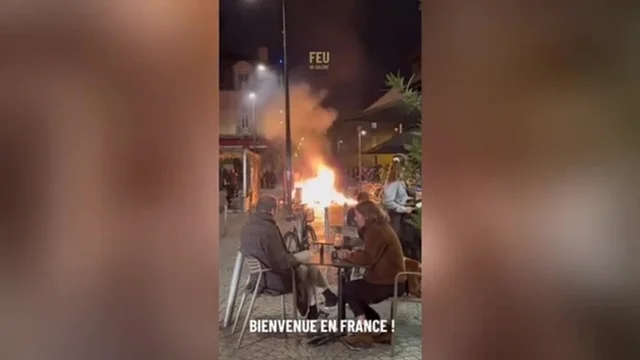 Coppia al bar mentre la città va a fuoco, le immagini virali dalla Francia